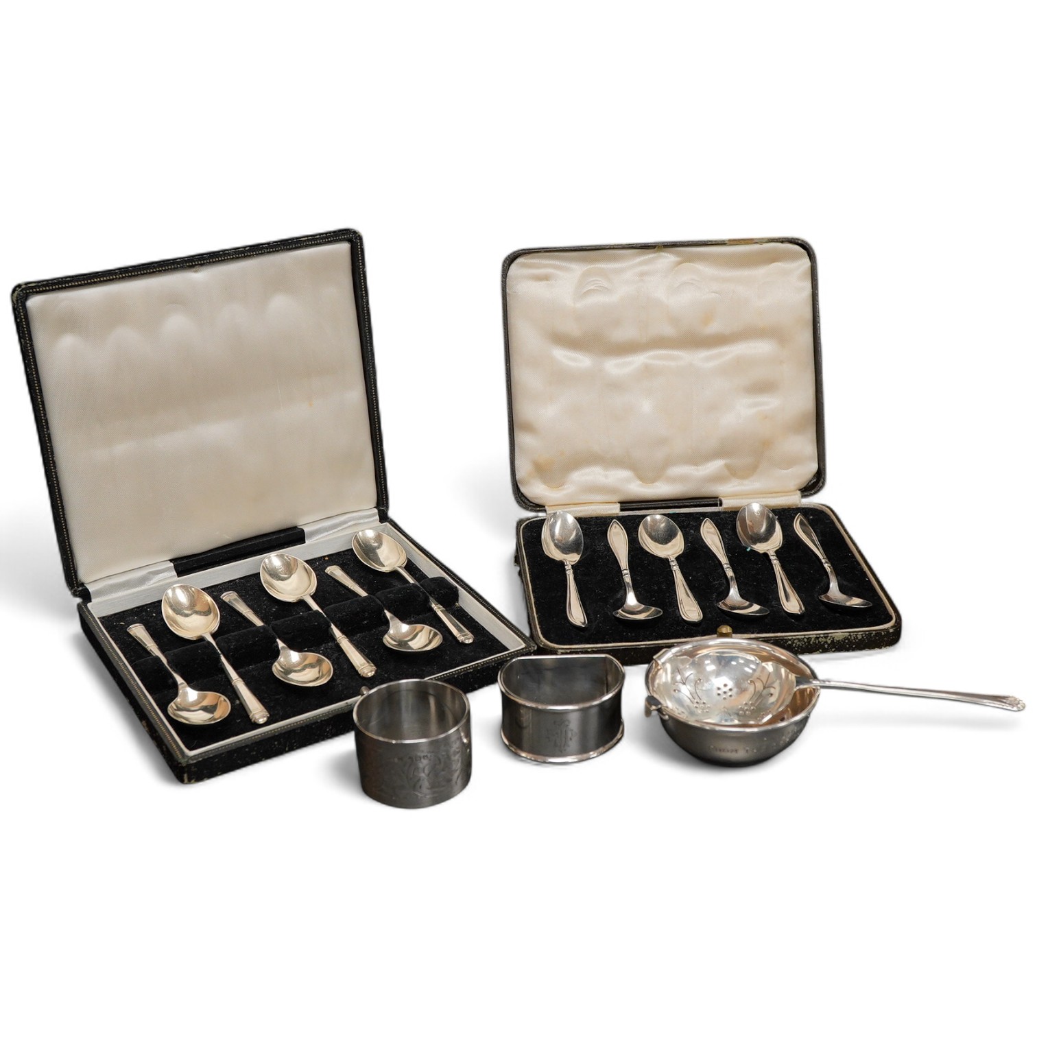 Two cased sets of six mid 20th century silver coffee spoons including Barker Brothers Silver Ltd, Birmingham, 1940, together with a silver and sterling napkin rings and a silver tea strainer on stand.